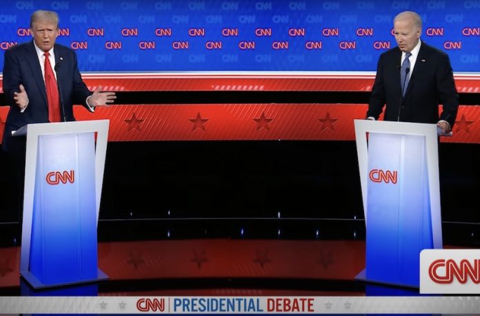 1-debate U.S. President Biden and Trump debate issues like immigration, border security and more from behind podiums on a stage.