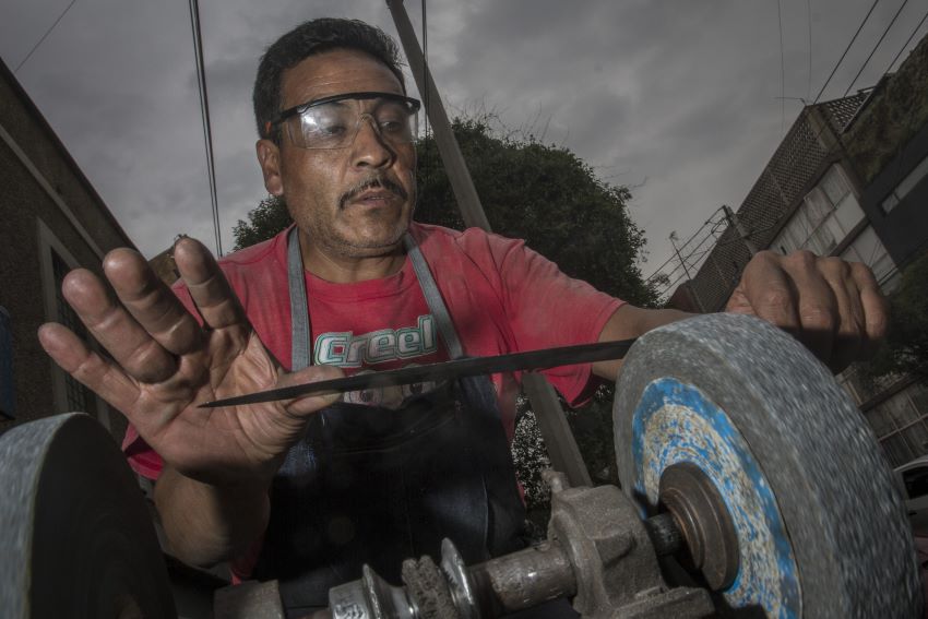 Knife sharpener at Mexico City, wearing glasses to protect his eyes.