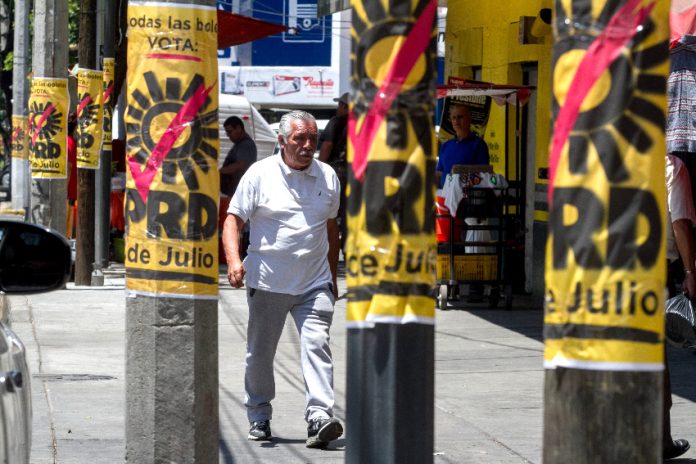 654925_Doctores Propaganda Electoral-1_impreso_850 A man walks by PRD campaign posters on posts in Mexico City
