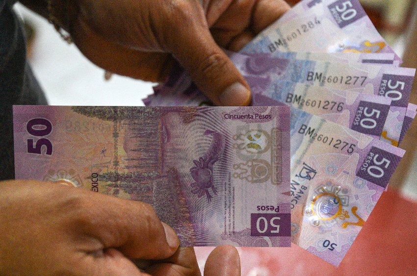 Hands holding 50 peso notes