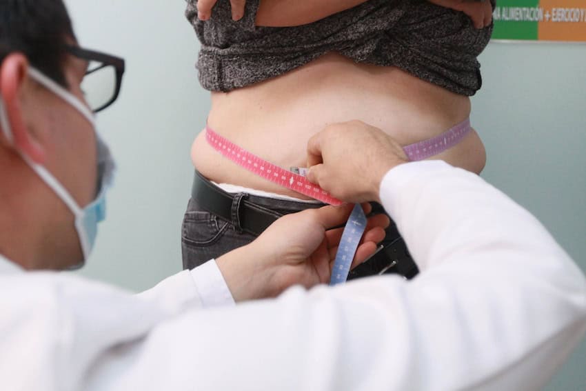An obese woman being measured by a doctor