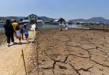 Family walking toward a marina in the Miguel Aleman reservoir in Mexico state. The lake bed they are walking on is cracked mud with no water.
