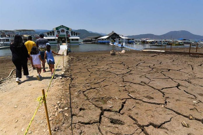 974796_Presa Valle de Bravo al 26.5_almacenamiento -6.jpg _web Presa Miguel Aleman - Crisanta Espinosa Aguilar Cuartoscuro Family walking toward a marina in the Miguel Aleman reservoir in Mexico state. The lake bed they are walking on is cracked mud with no water.