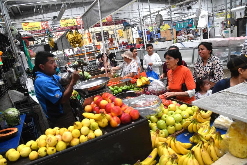 Vendor and customers at a fruit and vegetable market stall