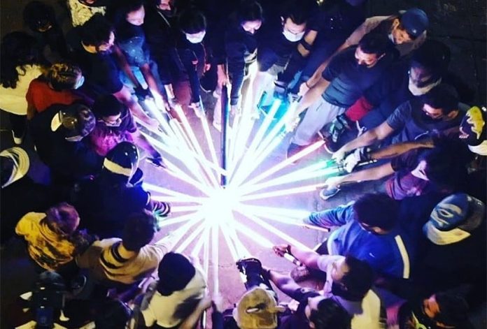 Circle of Lightsabers - JKA MX FB Members of the Jedi Knight Academy Mexico City at night gathered in a circle with each person extending their incandescent lightsabers to touch all together at the circle's center.