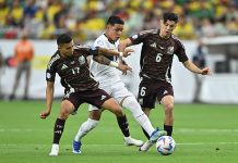 Two Mexican soccer players in red uniforms go after an Ecuadorian player in white with the ball, before Mexico was eliminated from the Copa América.