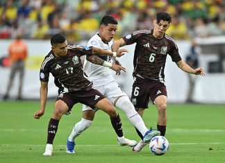 Two Mexican soccer players in red uniforms go after an Ecuadorian player in white with the ball, before Mexico was eliminated from the Copa América.