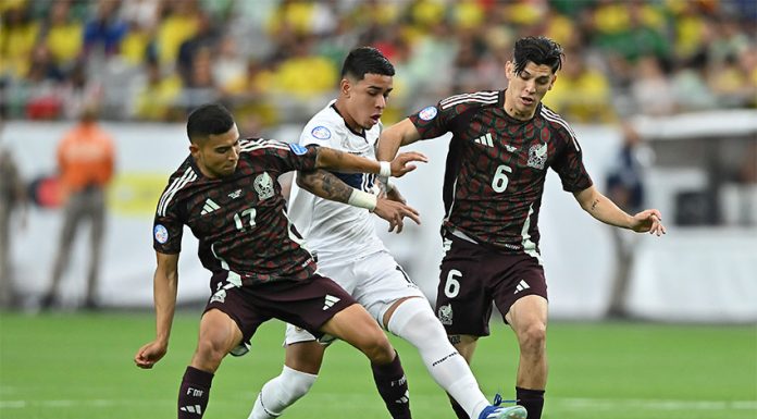 Two Mexican soccer players in red uniforms go after an Ecuadorian player in white with the ball, before Mexico was eliminated from the Copa América.