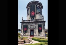 Part of Chapultepec Castle with what looks like three black and red banners hanging from it
