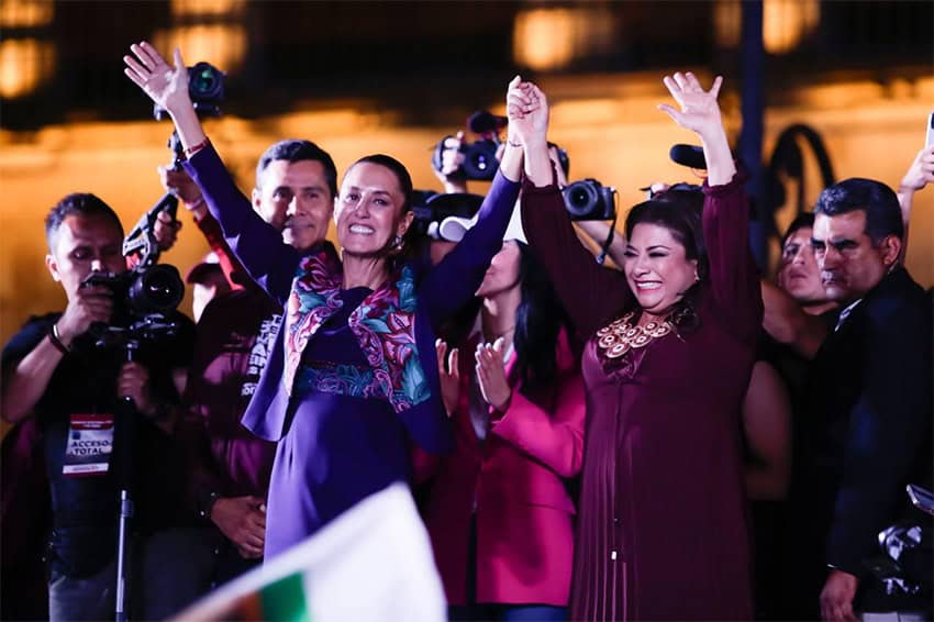 Clara Brugada and Claudia Sheinbaum hold their hands in the air to celebrate their electoral wins.