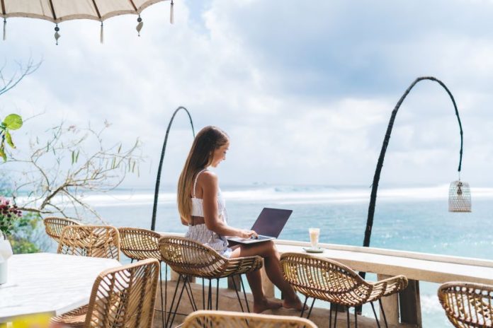 shutterstock_2337305117 girl working from the beach as a digital nomad