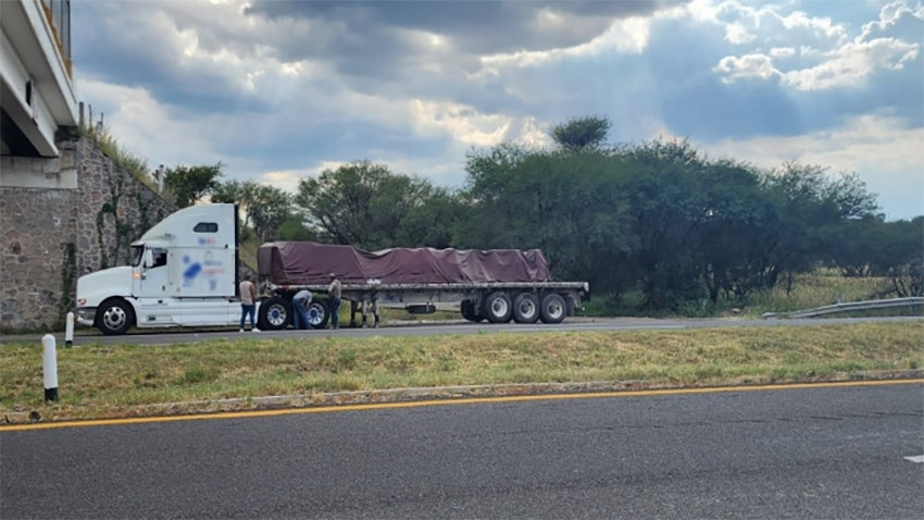 A loaded semi-trailer parked on the side of a highway.