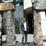 Travis Bembenek standing next to giant stone statues